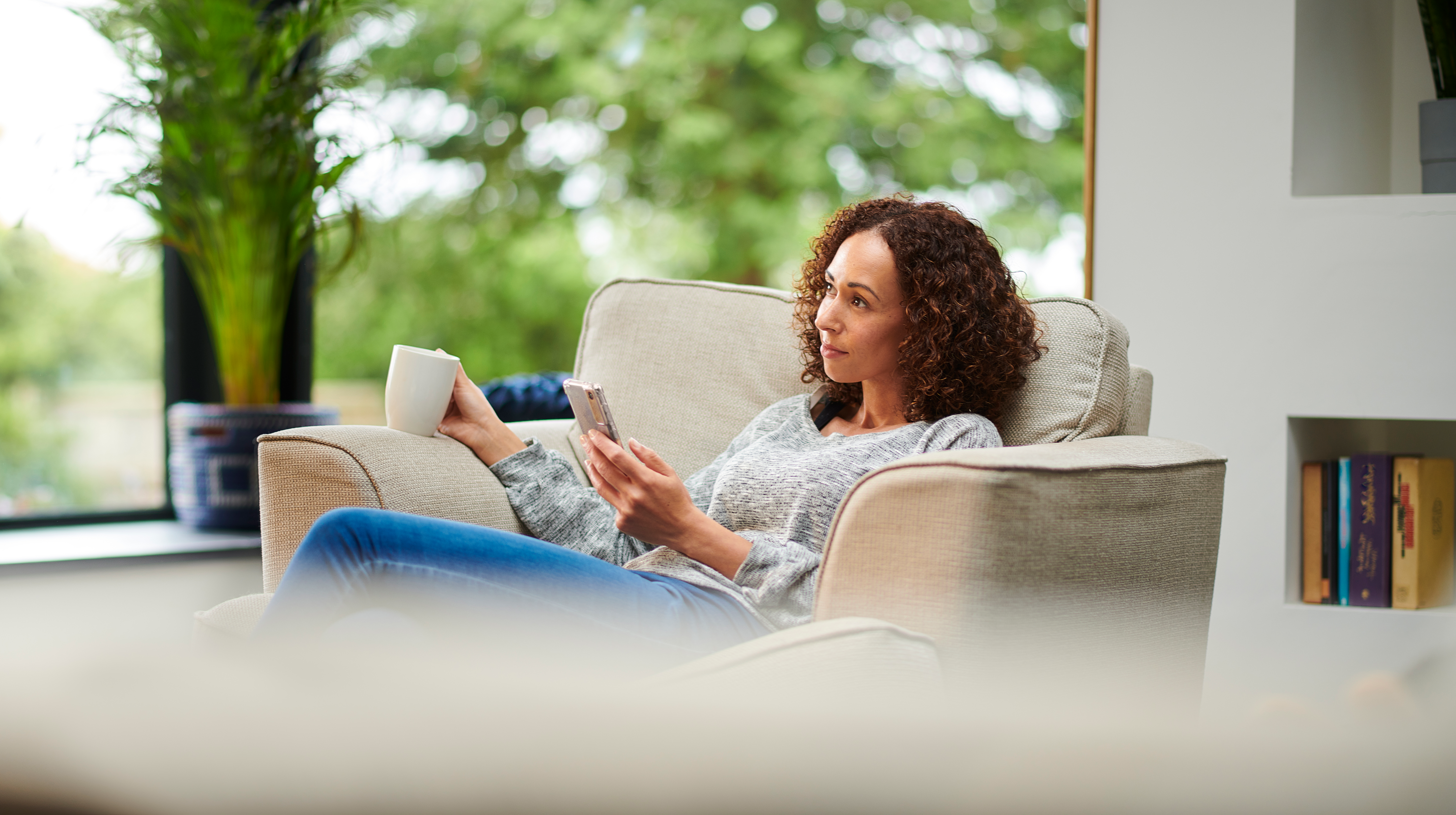 Person on couch with phone and coffee