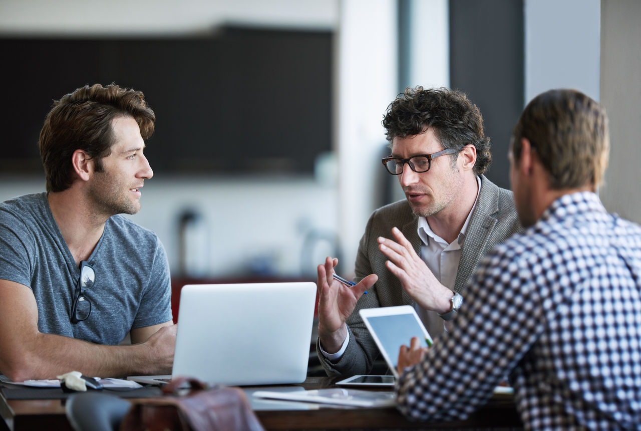 Cropped shot of three businessman discussing work in the office