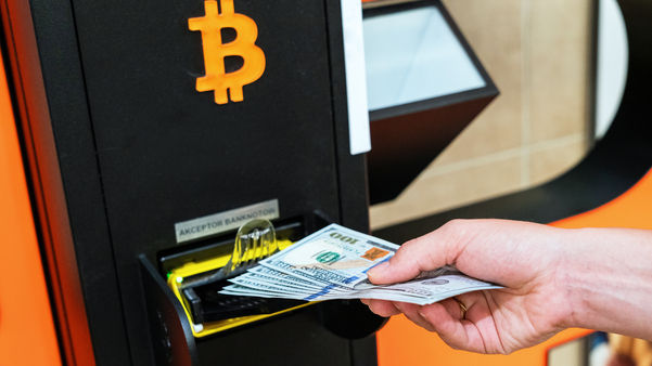 hand putting currency in a bitcoin atm 