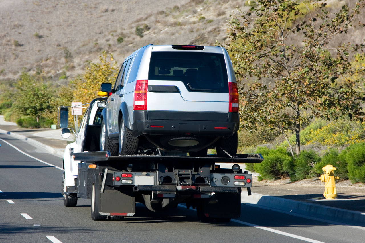 A tow truck towing a silver suv.