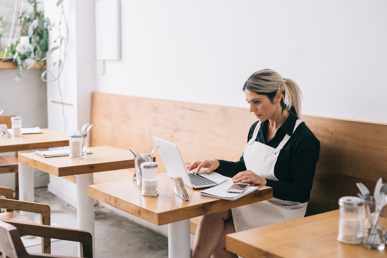 Cafe Manager paying bills and wages, maintaining inventory by using technology.
