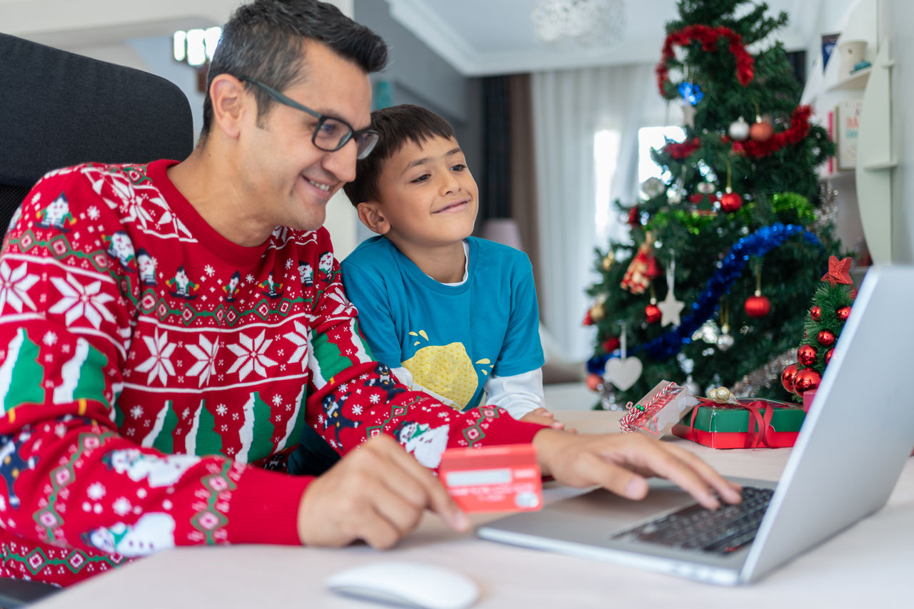 Men In Red Sweater Buying Presents Online With Son At Home