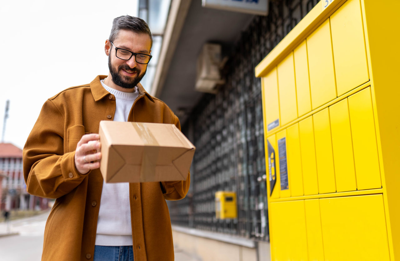 Mid adult smiling man collecting his package from a parcel shop