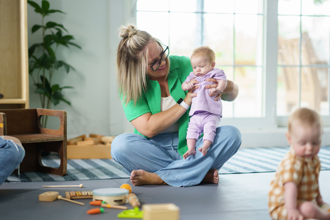 A nurturing scene of a mother interacting with babies in a sunlit and cozy living space.