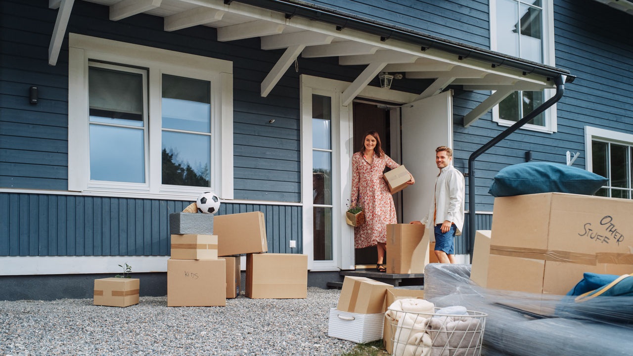 Young Family Moving to Their New Home in Residential Area. Handsome Man Unloading a Cargo Van Full of Cardboard Moving Boxes. Delivery Transportation Car Sharing Service.