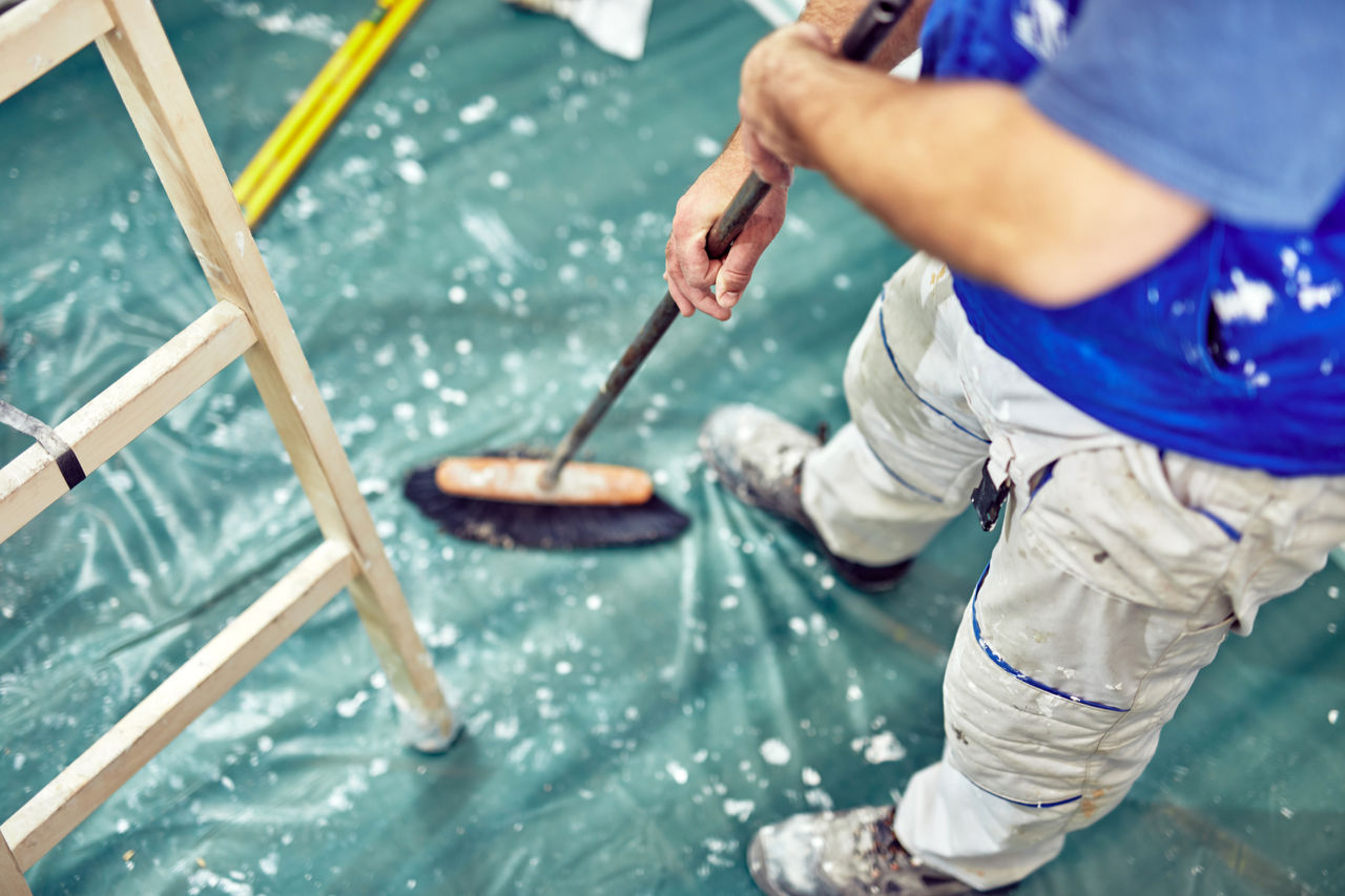 Worker using broom for cleaning dirt during renovaton of the house.