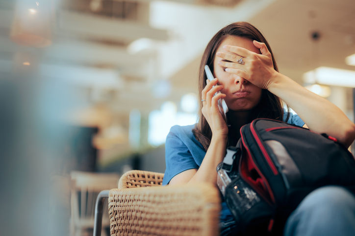 Stressed traveler speaking on her cellphone feeling overwhelmed