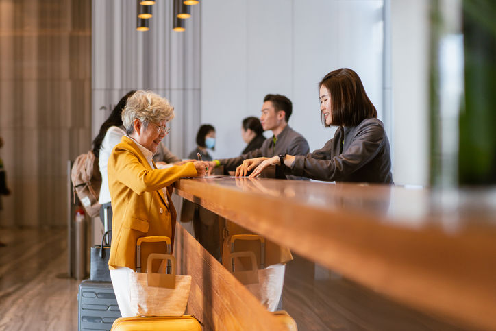 Business travel - Senior Asian businesswoman checking into a hotel