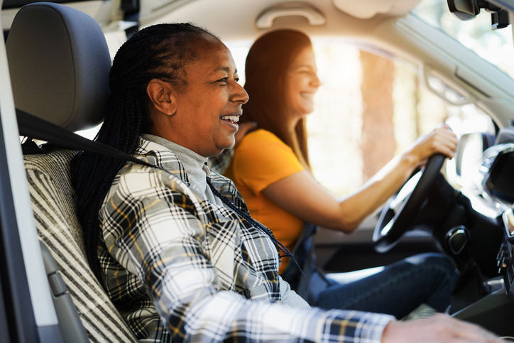 Happy senior women having fun traveling with camper van during autumkn vacation - Travel, multiracial and friendship concept - Focus on african female face