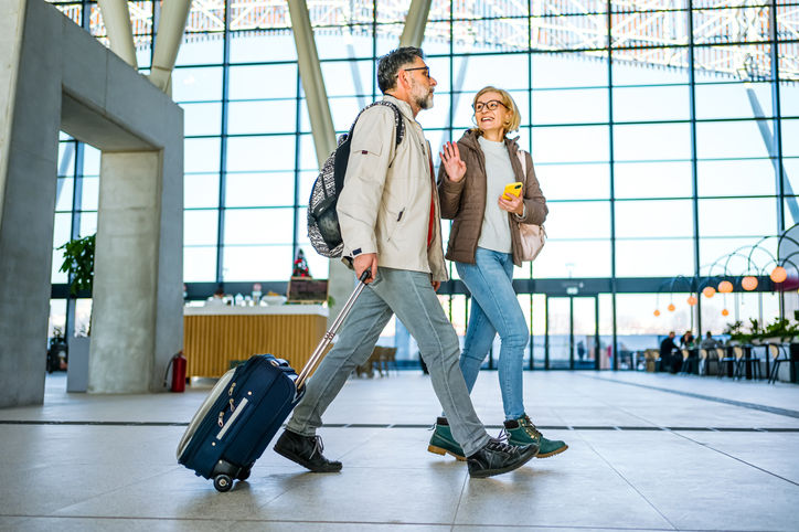 Cheerful mature couple of passengers with luggage at the train station