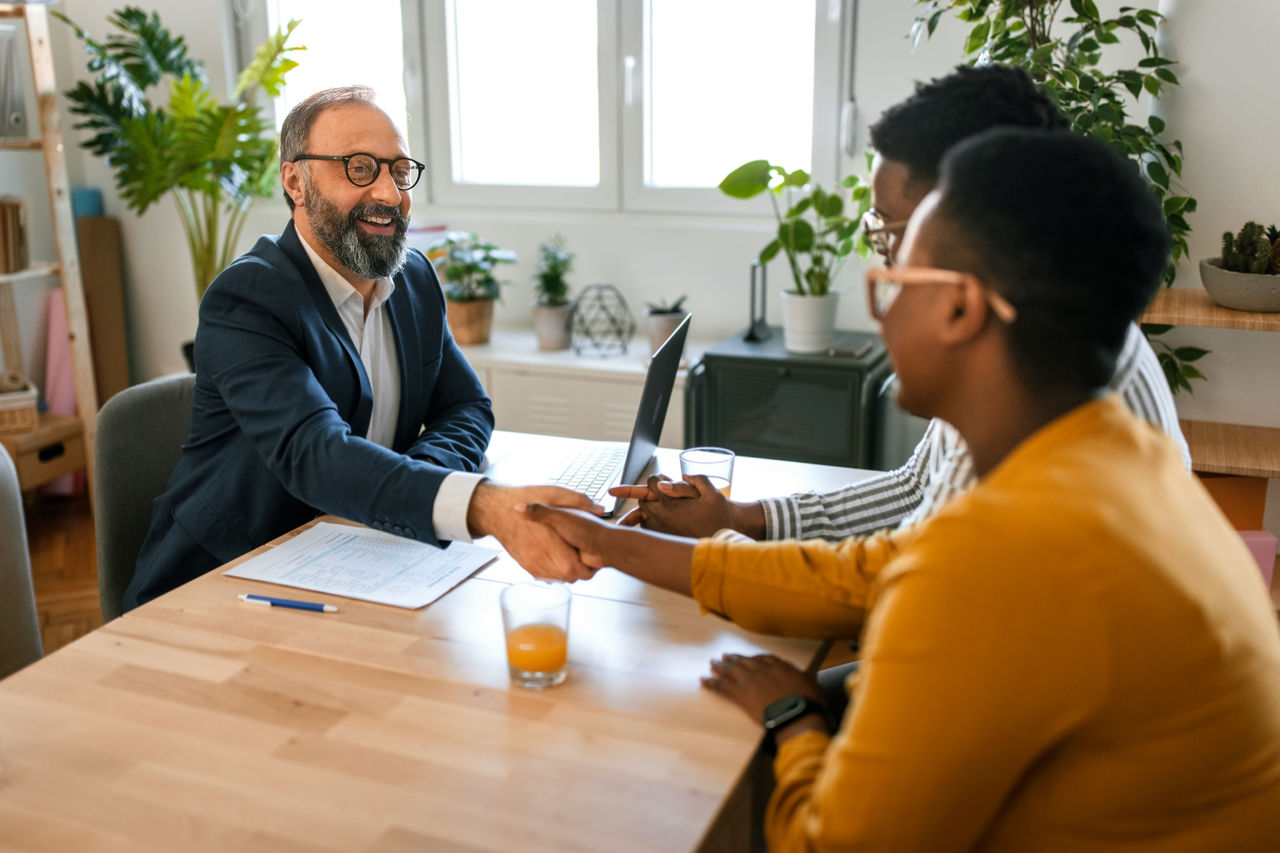 Grateful black family couple handshake with insurer before signing contract