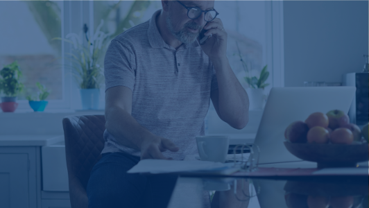 man on the phone in kitchen looking at computer with dark blue overlay