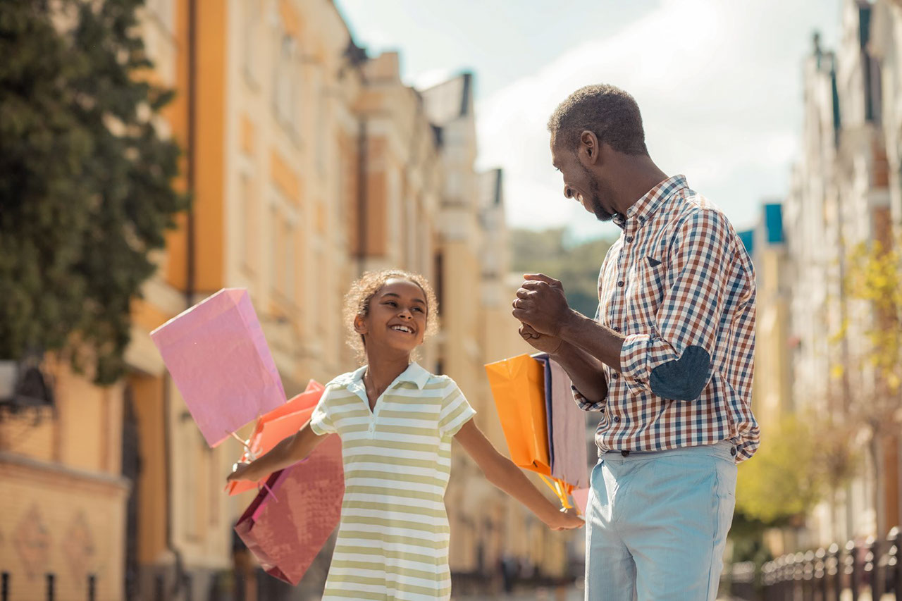 Father and daughter walking and smiling with shopping bags