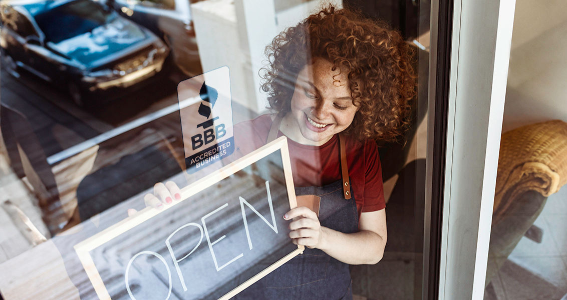 Cheerful female multi racial business owners standing with open sign in front of hair salon.