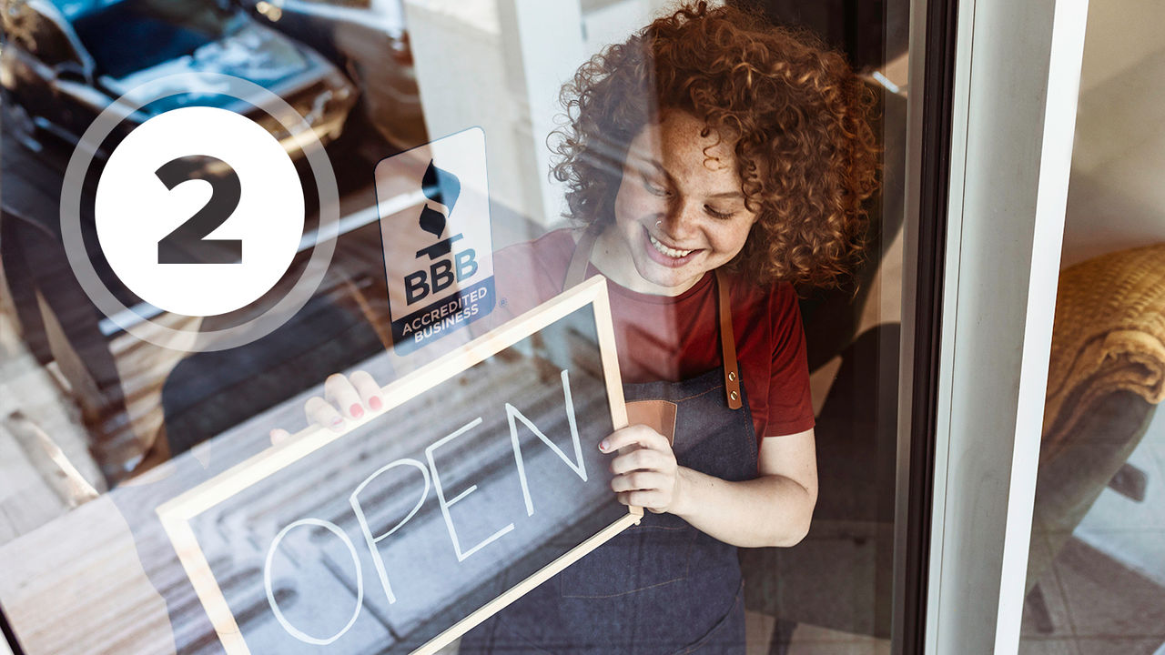 Cheerful female multi racial business owners standing with open sign in front of hair salon.