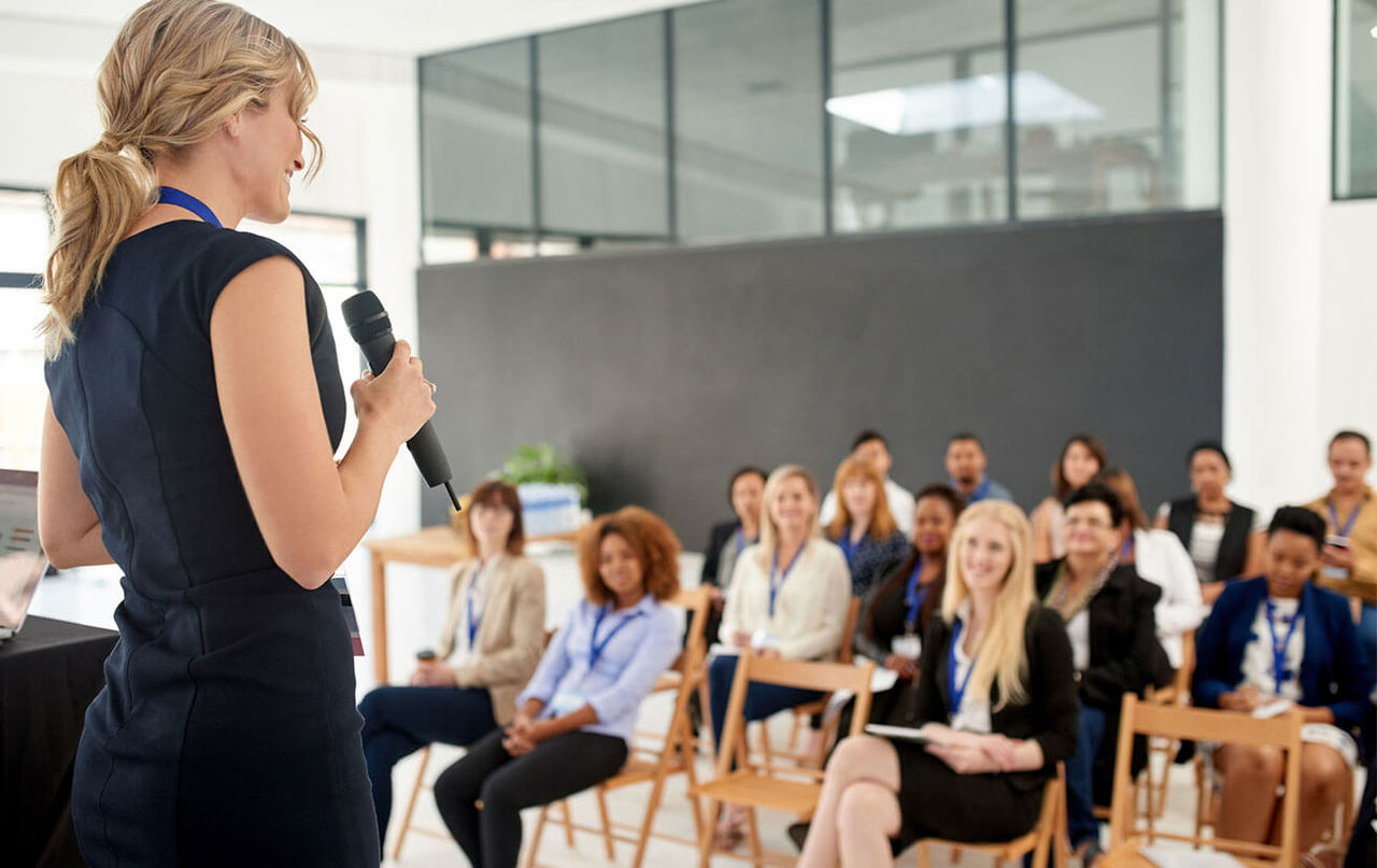 Woman speaking in front of group of people at event