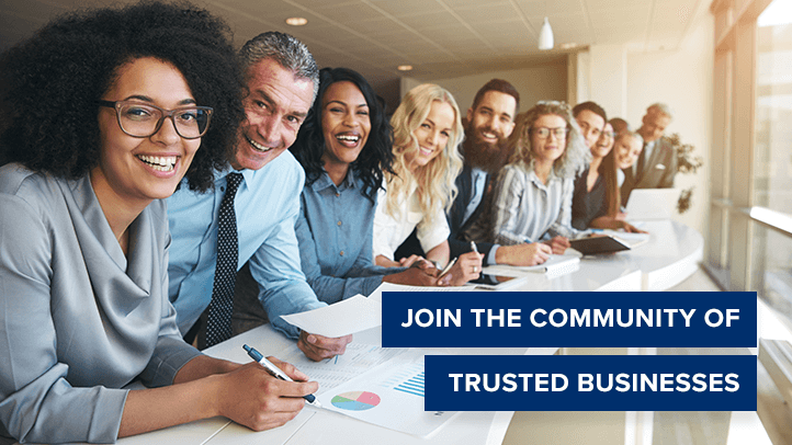 Group of people in business clothes around a counter top looking and smiling at camera with text Join the community of trusted businesses