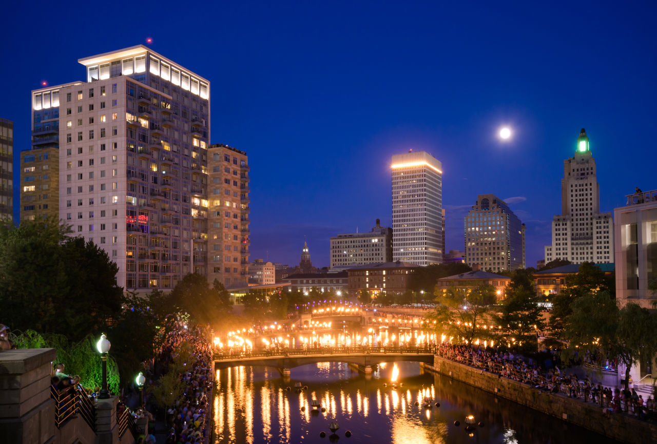 Crowds gather along Woonasquatucket river in Providence, RI for the summer series known as WaterFire, which consists of fiery wooden blocks placed along the river during the nighttime.