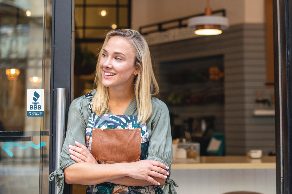 Woman standing in front of shop with an accredited business seal