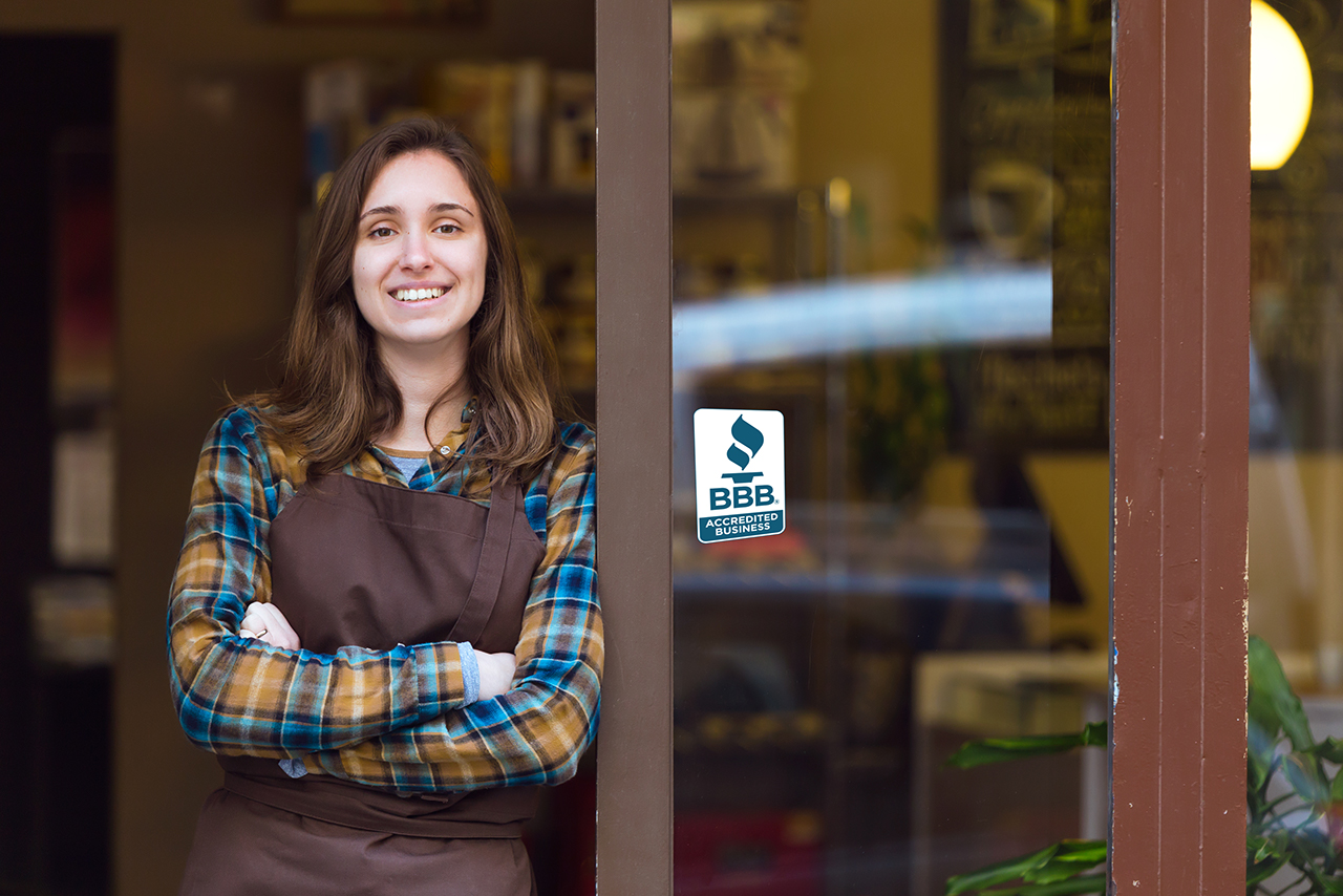 Business owner standing in doorway with BBB Accredited Business seal on window