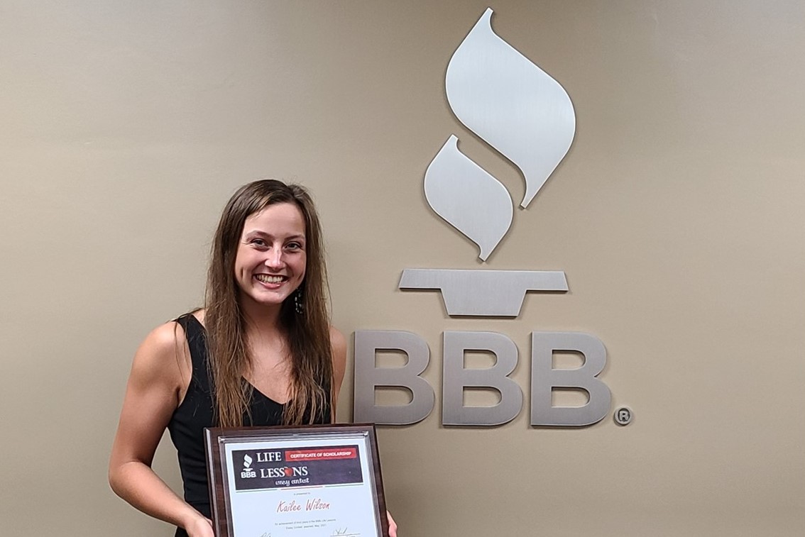 Kailee Wilson 2021 3rd place winner holding award certificate next to BBB sign