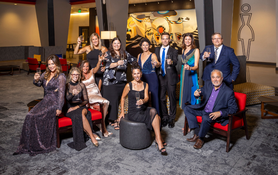 2024 Torch Awards for Ethics and Spark Awards winners, some sitting and some standing in a hotel lounge, toast to ethical excellence.