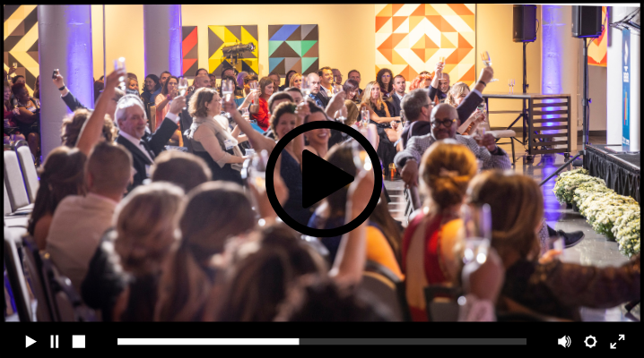 still of video showing crowd raising champagne glasses at an awards show