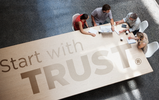 start with trust text overlaying a table with workers collaborating