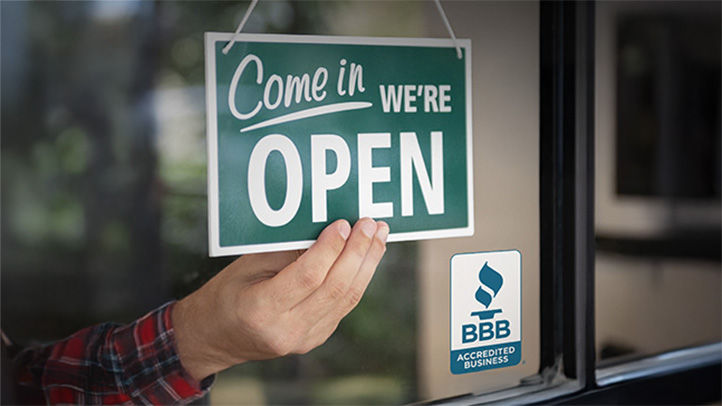 a man's hand flipping and open sign next to the BBB accredited business seal