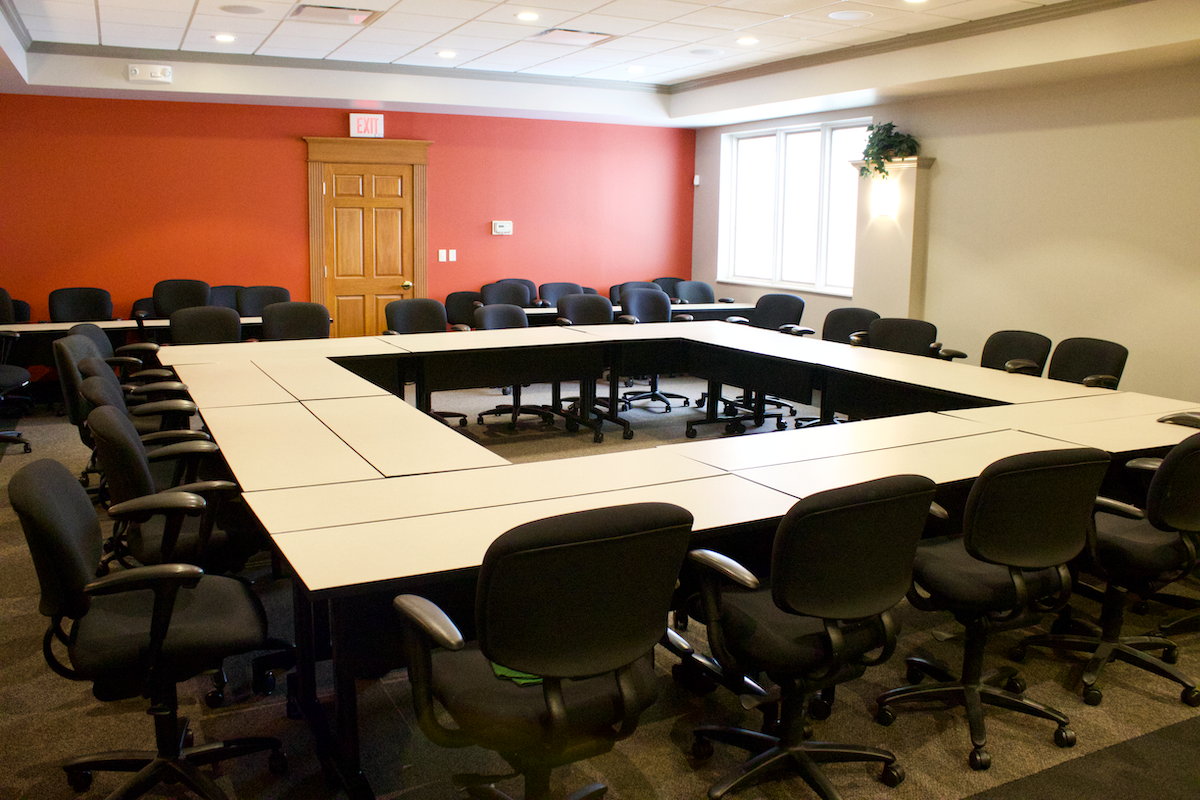 Picture of large board room with desks arranged in square formation in center of room