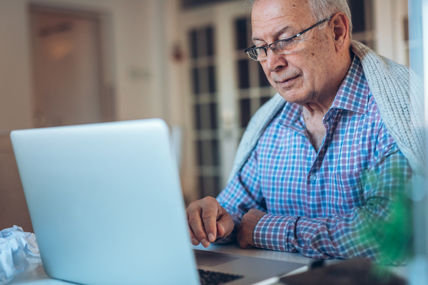 Photo of senior man works on a lap top at home