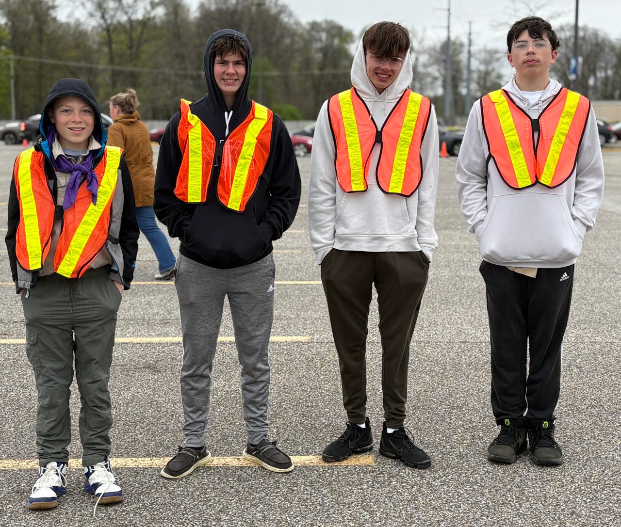 4 smiling teenaged boys wearing orange vests