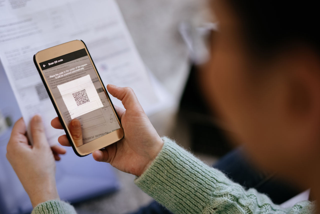 Mid adult woman scanning QR code with smart phone