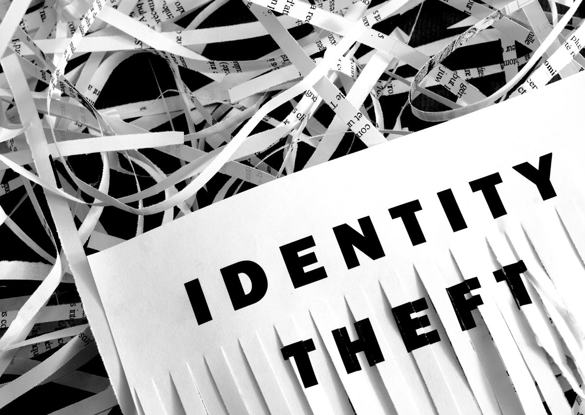 Black identity theft words on partially shredded white paper