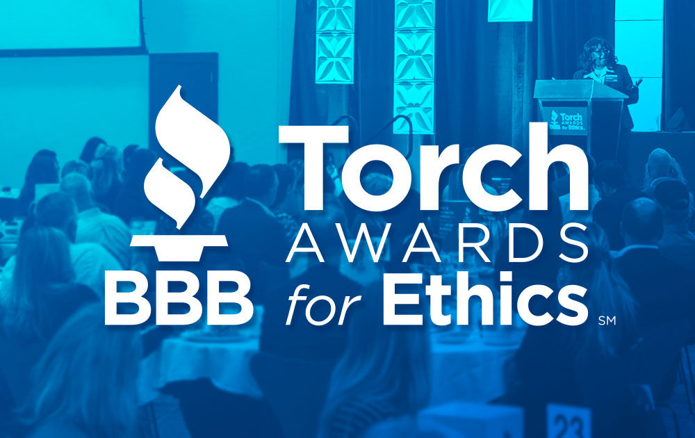 Large white "BBB Torch Awards for Ethics" logo on top of blue hued image of woman on stage at event