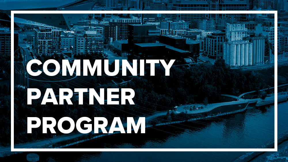 White text reading "Community Partner Program" inside white box outline over blued image of city
