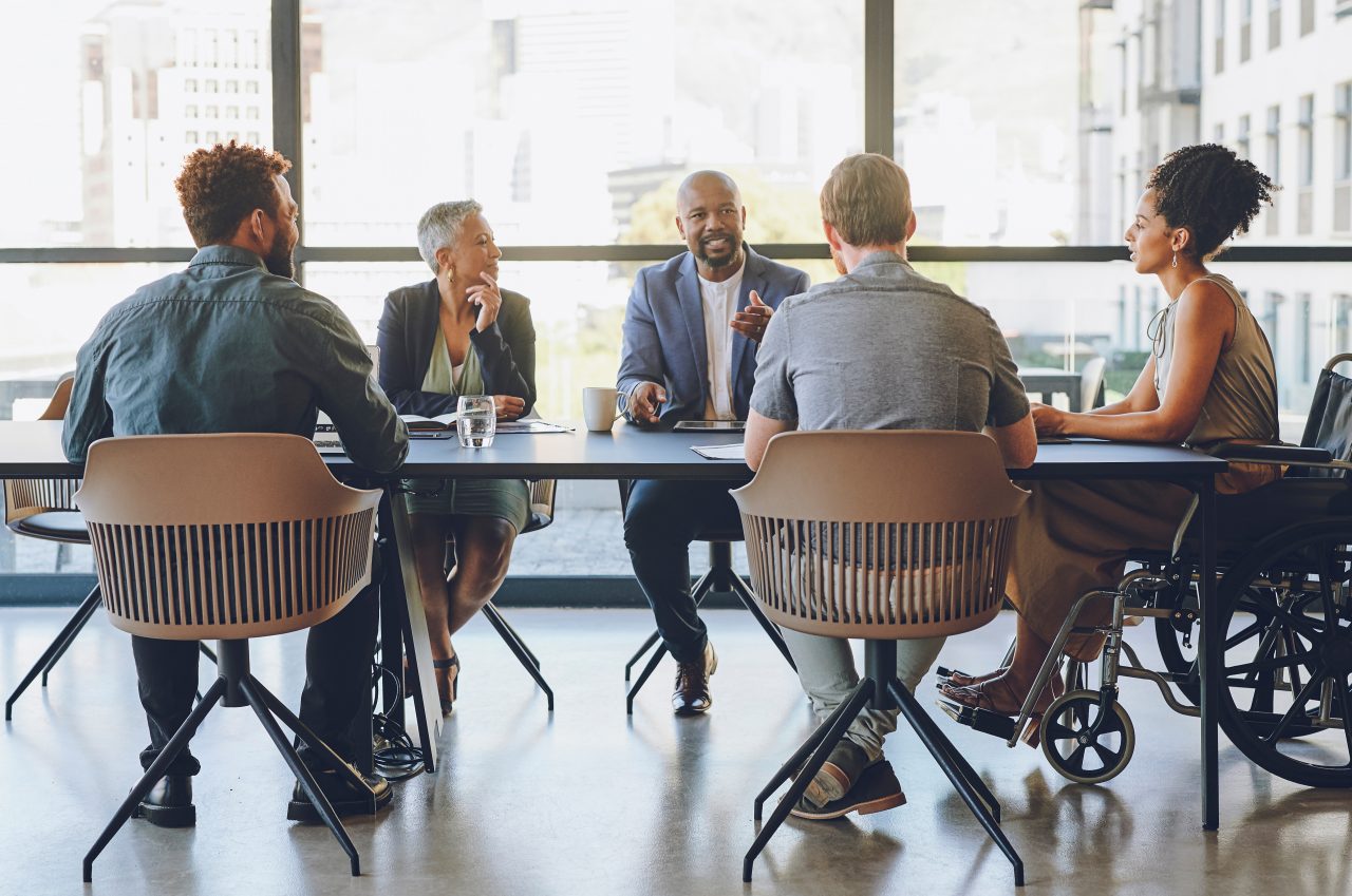 Disability, diversity and business meeting with staff, people or team communication, planning on corporate strategy, goal or mission for KPI. Woman in wheelchair in group talking of company inclusion