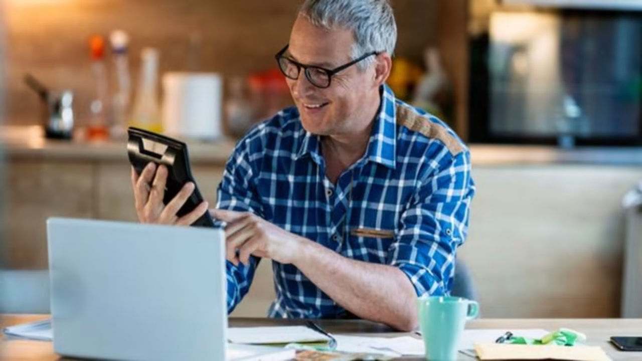 Man using a calculator and computer to do taxes