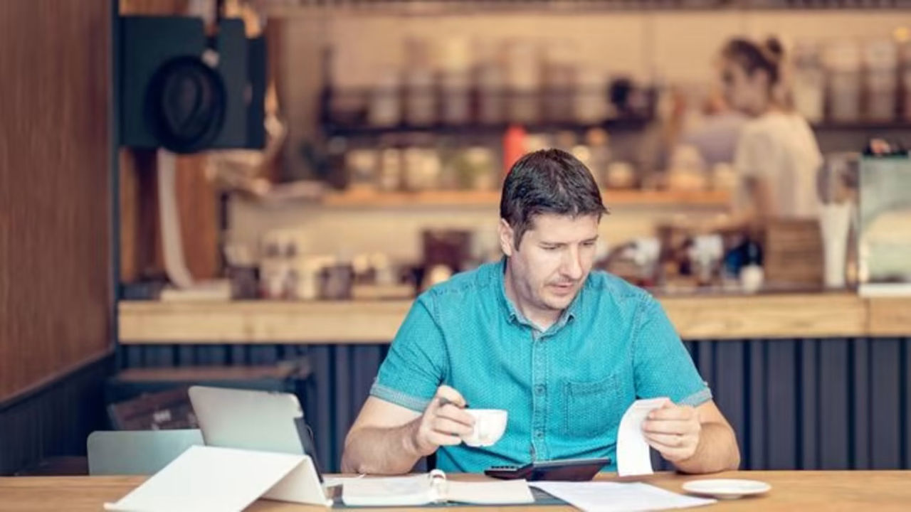 Man at coffee shop looking at receipts