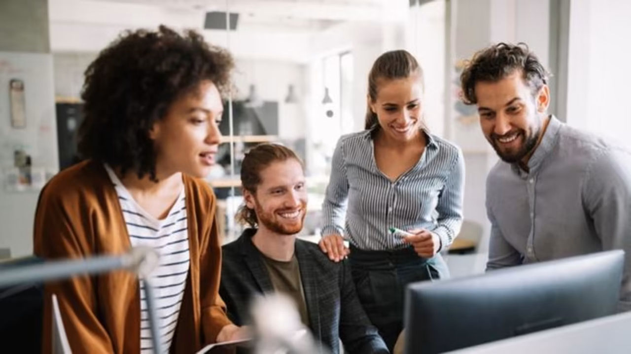 Group of employees with smiles looking at a computer