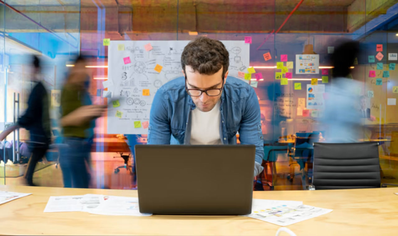 Man working on a computer at a busy company