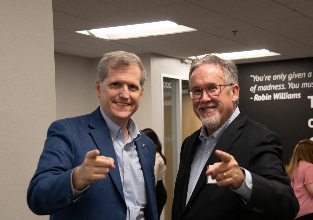 Two men smiling and pointing at the camera