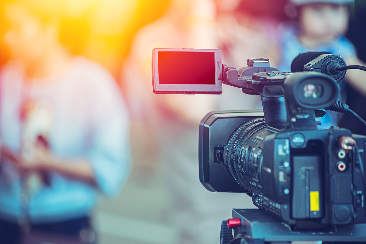 Video camera camcorder operator working at live event broadcasting blue color tone.