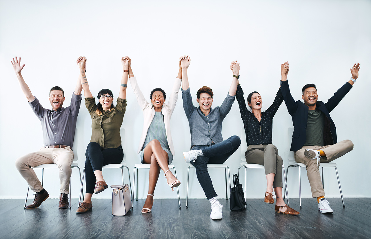 Studio shot of a group of businesspeople holding hands and cheering in a waiting room