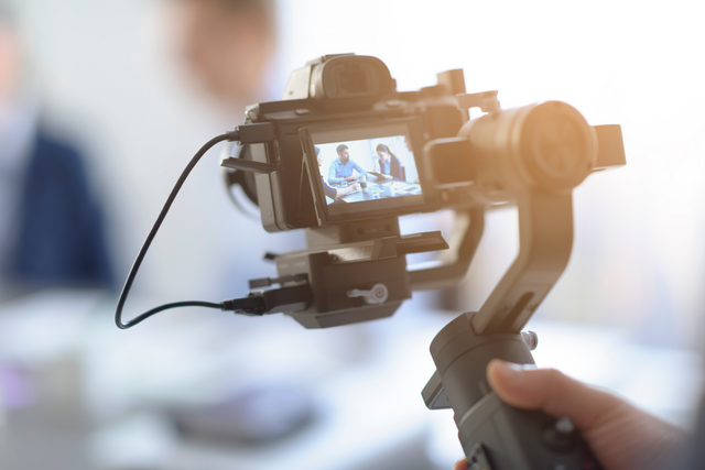 A person holds a camera that is recording people at work in an office