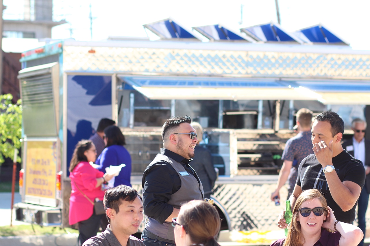 Group of people outside gathered around food trucks 