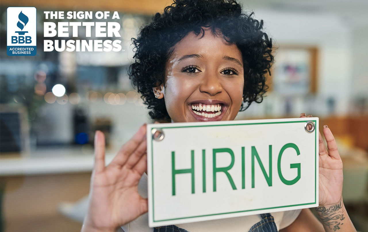 Smiling woman holding a hiring sign