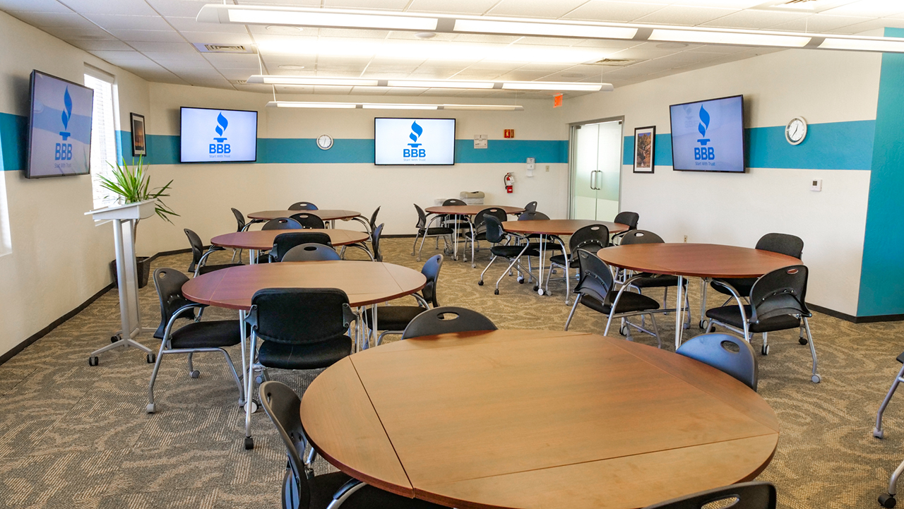 large room with many round brown, round tables and large screen televisions on the walls