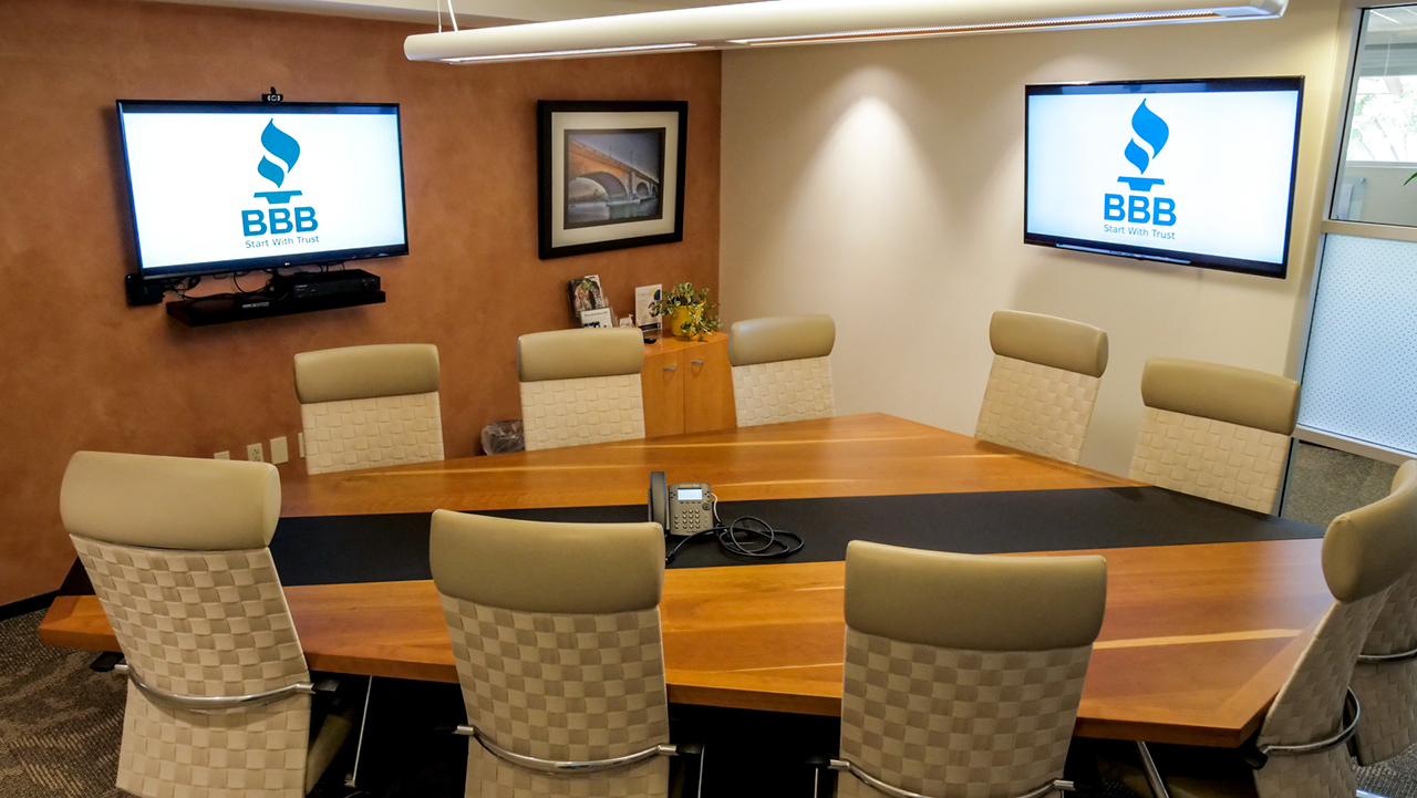 conference room with polygon shaped table and television screens on the walls