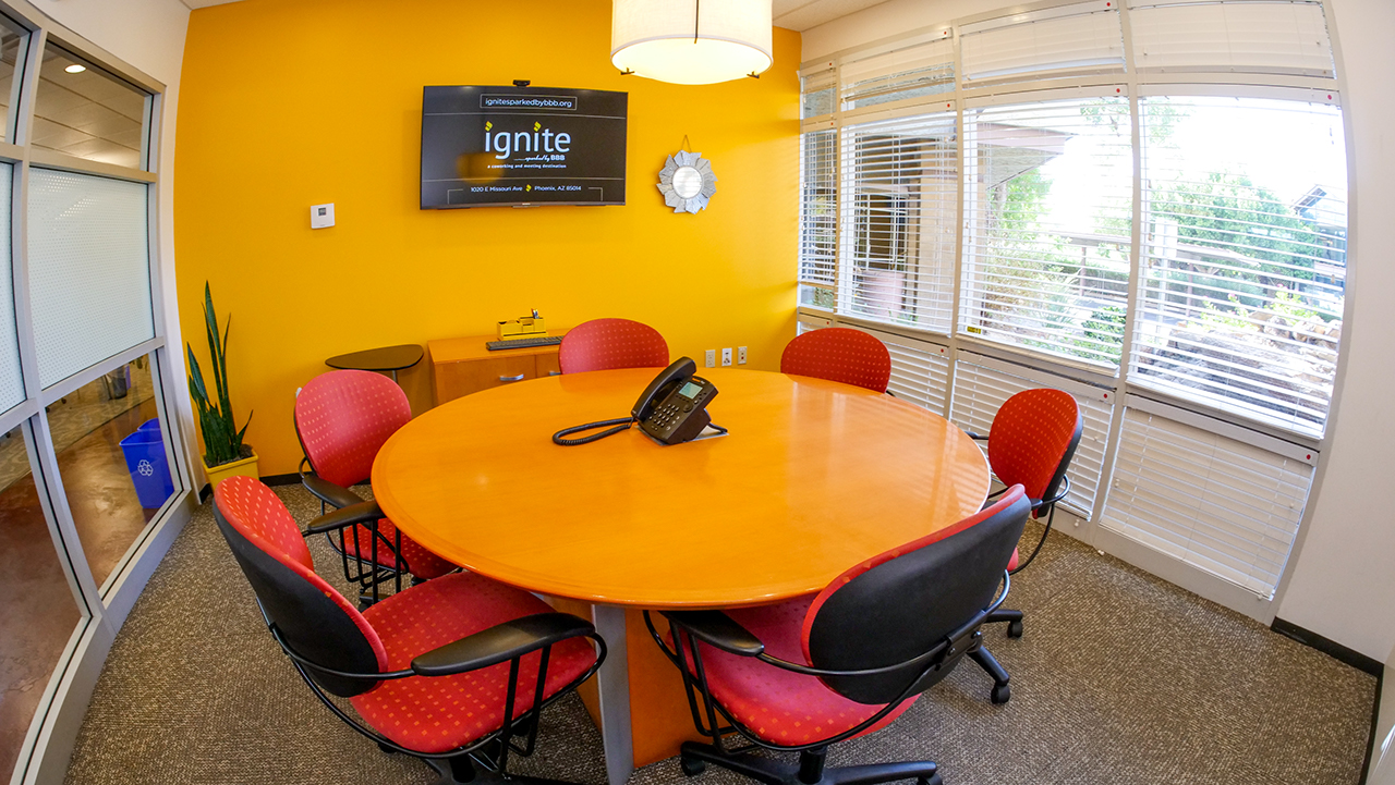 small round table with a tv on the yellow wall and floor to ceiling windows